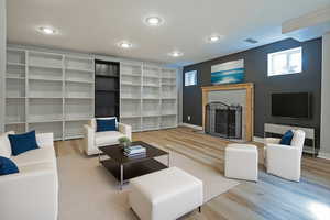 Living room with wood finished floors, a brick fireplace, and recessed lighting