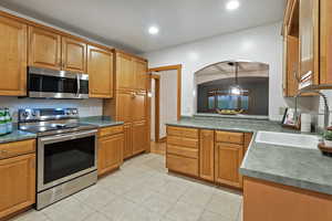 Kitchen featuring stainless steel appliances, brown cabinets, light tile patterned floors, and recessed lighting