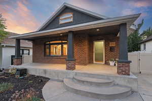 Back of house with brick siding and covered porch
