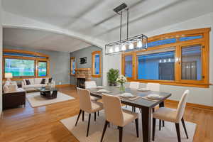 Dining area with a fireplace, light wood finished floors, and arched walkways