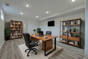 Office with light wood-style flooring and recessed lighting