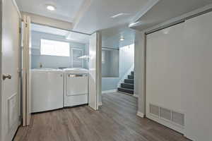 Laundry area with wood finished floors, separate washer and dryer, and recessed lighting