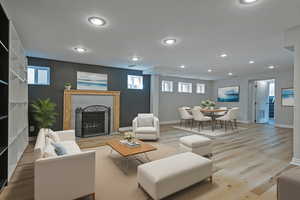 Living room with a fireplace, wood finished floors, and recessed lighting