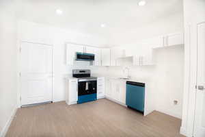 Kitchen with white cabinets, stainless steel appliances, light wood-type flooring, and recessed lighting