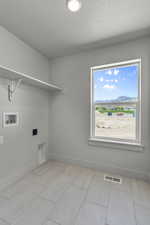 Laundry area with a mountain view, hookup for a washing machine, and light tile patterned floors