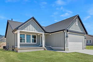 Modern farmhouse style home with roof with shingles, board and batten siding, a front yard, and an attached garage