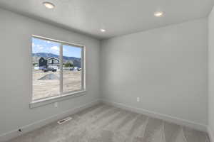 Unfurnished room with light colored carpet and recessed lighting