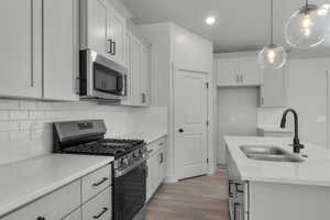 Kitchen featuring appliances with stainless steel finishes, backsplash, decorative light fixtures, dark wood finished floors, and light stone countertops