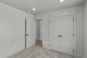 Unfurnished bedroom featuring light colored carpet, a closet, and recessed lighting