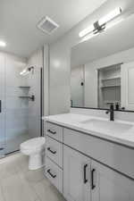 Bathroom featuring a spacious closet, a stall shower, vanity, and light tile patterned flooring