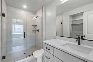 Full bathroom with vanity, a stall shower, a walk in closet, and light tile patterned flooring