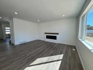 Unfurnished living room with a fireplace, dark wood-style flooring, and recessed lighting