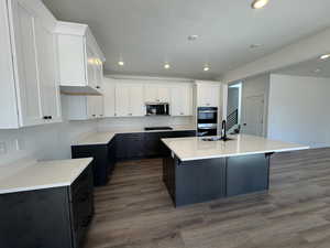 Kitchen with white cabinetry, dark cabinetry, a center island with sink, dark wood-style flooring, and recessed lighting