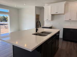 Kitchen featuring dark cabinets, dark wood-style flooring, white cabinetry, light stone countertops, and recessed lighting