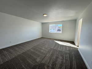 Spare room with dark colored carpet and a textured ceiling