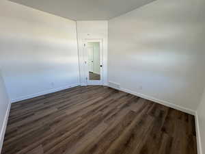 Empty room with dark wood-style floors and baseboards
