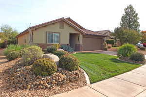 Mediterranean / spanish-style home featuring stone siding, stucco siding, a front yard, and an attached garage