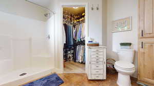 Bathroom featuring a spacious closet, light tile patterned flooring, and a stall shower