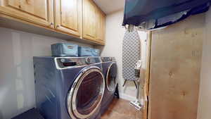 Washroom with cabinet space, dark tile patterned flooring, and washing machine and dryer