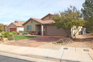 View of front of house featuring stone siding, driveway, stucco siding, a garage, and a tile roof