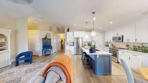 Kitchen with appliances with stainless steel finishes, backsplash, pendant lighting, white cabinets, and a kitchen breakfast bar