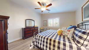 Bedroom featuring lofted ceiling, light wood finished floors, and a ceiling fan