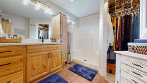 Full bathroom with a spacious closet, vanity, light tile patterned flooring, and a stall shower