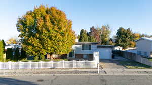 View of front of home with concrete driveway, a fenced front yard, and a garage