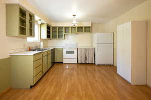 Kitchen featuring white appliances, light countertops, light wood-type flooring, a textured ceiling, and green cabinetry