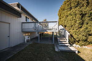 View of green lawn with a deck, stairway, and a patio area