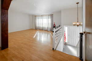 Spare room with a chandelier and light wood finished floors