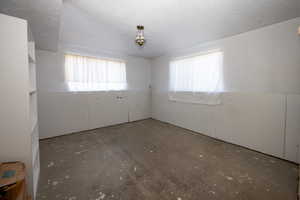 Unfurnished room featuring unfinished concrete flooring and wainscoting