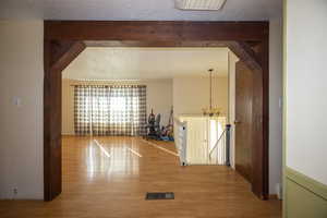 Corridor featuring an upstairs landing, a textured ceiling, and wood finished floors