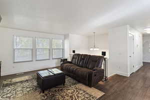 Living area featuring a chandelier and dark wood-type flooring