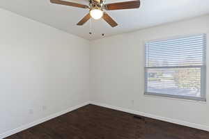 Empty room with dark wood-type flooring and a ceiling fan