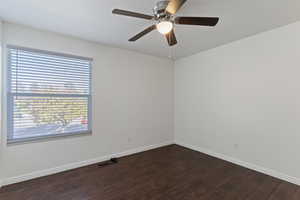 Empty room with dark wood finished floors and a ceiling fan