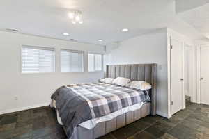 Bedroom featuring a textured ceiling, stone tile floors, and recessed lighting
