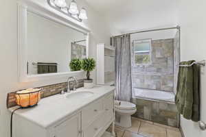 Bathroom with tiled shower / bath combo, vanity, decorative backsplash, and light tile patterned floors