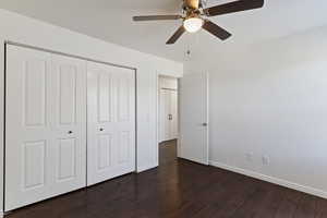 Unfurnished bedroom featuring dark wood finished floors, a closet, and a ceiling fan