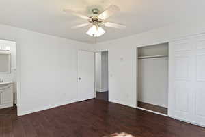 Unfurnished bedroom with dark wood finished floors, ceiling fan, a closet, and connected bathroom