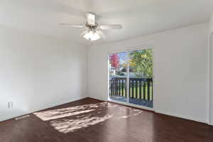 Unfurnished room featuring dark wood finished floors and a ceiling fan