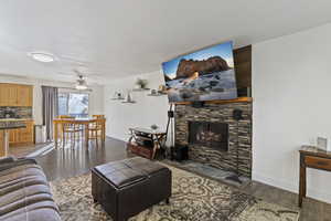 Living room with dark wood-style floors, a fireplace, and ceiling fan