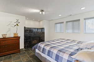 Bedroom featuring a fireplace, dark stone finish flooring, and recessed lighting