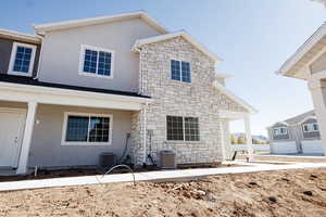 Rear view of house featuring stucco siding and stone siding