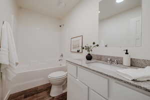 Bathroom with shower / tub combination, vanity, and dark wood-type flooring