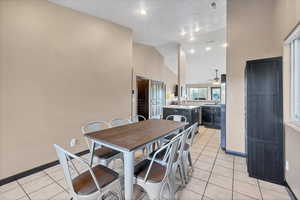 Dining room featuring light tile patterned floors, high vaulted ceiling, a ceiling fan, and recessed lighting