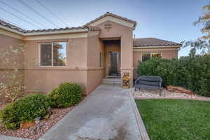 Entrance to property with stucco siding, a tile roof, and a yard