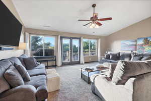 Living room featuring vaulted ceiling, carpet, and a ceiling fan