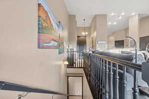 Corridor with a chandelier, an upstairs landing, and a towering ceiling