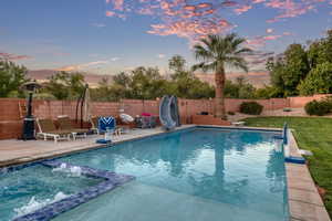 View of swimming pool with a water slide, a pool with connected hot tub, and a fenced backyard